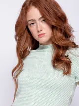 Remera corta color amarillo con estampado de lunares blancos, cuello alto y mangas cortas.