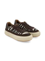 Championes urbanos con diseño de paneles en gamuza marrón y detalles en pelo sintético con estampado animal print de cebra. Presentan suela de plataforma color crema con base de goma y cordones al tono.