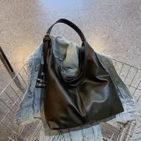 Bolso tipo hobo de cuero sintético negro con asa de hombro ajustable.