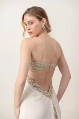 Vestido largo marfil de gasa, strapless, con bustier bordado en pedrería brillante y diseño drapeado en el frente.