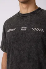 Remera negra con efecto acid wash, corte holgado y estampa frontal con logos y diseño de automovilismo.
