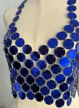Top tipo corpiño confeccionado con círculos metálicos unidos por pequeñas cadenas, color azul eléctrico. Se ajusta con cadenitas en la espalda y el cuello.