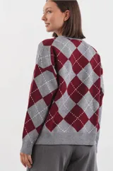 Sweater de punto con diseño de rombos estilo argyle en tonos gris y bordó. Presenta cuello redondo y terminaciones acanaladas en puños y cintura.