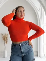 Polera tejida color naranja, de corte crop y cuello alto.