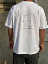 Remera blanca de corte oversize con estampado en la espalda que incluye dos círculos intersecados con las palabras 'Surf', 'Life' y 'Skate', y las frases 'Real Experience', 'Coexist' y 'Meaningful Day'.