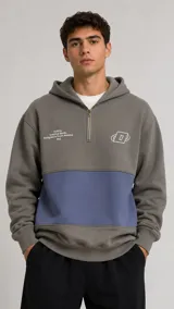 Hoodie de corte holgado con cierre frontal parcial, diseño de bloques de color en gris y azul, y estampado gráfico en el pecho.