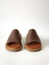 Sandalias de cuero color chocolate, con faja ancha en el empeine, plantilla de gamuza y suela plana con taco bajo.