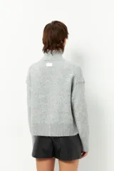 Polera de tejido de punto color bordó, con cuello alto, manga larga y costura vertical central en el frente.