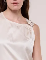 Blusa de satén color negro, de corte fluido, con escote asimétrico y un aro metálico decorativo en el hombro.