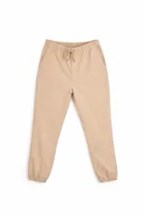 Pantalón tipo jogger de color beige, con cintura elástica y cordón ajustable, bolsillos laterales y puños elásticos en los tobillos.