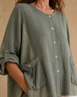 Blusa verde militar de lino con detalles de broderie en los laterales y mangas, cuello redondo, cierre frontal abotonado y bolsillos frontales con solapa.