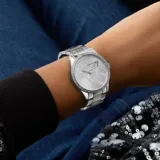 Reloj analógico Guess modelo Roxy con caja de 36 mm y malla de acero inoxidable en tono plateado. La esfera presenta el logo de la marca con un diseño triangular central y el bisel está decorado con cristales brillantes.
