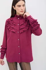 Camisa de manga larga en color rosado, con diseño de volados en cascada en el frente y en los puños. Presenta cuello alto con terminación suave y cierre frontal con botones.
