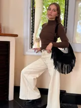 Cartera tipo hobo de cuero negro con diseño de flecos largos en los laterales. Cuenta con una correa de hombro integrada y cierre superior.