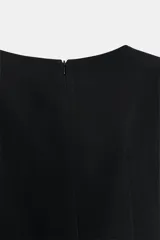 Vestido corto de color negro, con cuello redondo, manga corta abullonada y cierre de cremallera oculta en la espalda.