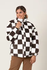 Campera de textura tipo peluche con diseño de cuadros damero en color marrón y blanco. Presenta cuello alto, cierre frontal completo y bolsillos laterales.