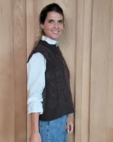 Chaleco de punto gris oscuro con diseño de trenzas y rombos en relieve, cuello redondo y terminaciones acanaladas.