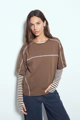 Remera de manga corta con silueta relajada y costuras a la vista en color blanco que contrastan sobre el tejido negro. Presenta un diseño moderno con terminaciones destacadas.