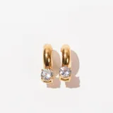 Aros tipo argolla dorados con un cristal redondo colgando.