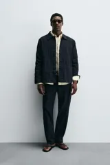 Sobrecamisa de algodón azul marino con textura jacquard de rayas verticales en relieve. Presenta cuello solapa, manga larga, cierre frontal de botones y dos bolsillos de parche grandes en la parte inferior delantera.