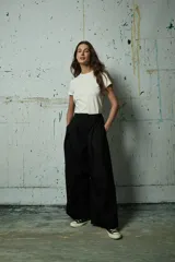 Pantalón de vestir negro de corte ancho y tiro alto, con pinzas frontales y cierre oculto.
