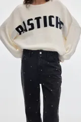 Sweater oversize de punto blanco con diseño jacquard de la inscripción Pastiche en color negro en el frente, de mangas largas y cuello redondo.