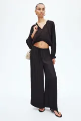 Pantalón marrón oscuro de corte holgado y piernas amplias, con cintura elástica fruncida y cordón ajustable.