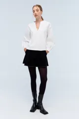 Blusa blanca de algodón con escote en V y mangas largas abullonadas.