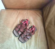 Sandalias de cuero marrón con tiras cruzadas y hebilla ajustable.