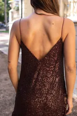 Vestido corto de lentejuelas color chocolate, con breteles finos, escote en V y volado en el ruedo.