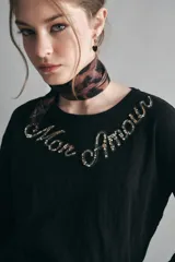 Remera de manga larga y calce relajado, confeccionada en algodón negro. Presenta un escote redondo y un bordado decorativo de piedras en el pecho con la frase 'Mon Amour'.