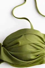 Top de bikini balconette verde militar con copas acolchadas, aros, pliegues fruncidos y detalle cruzado en el centro. Cuenta con breteles ajustables y desmontables.
