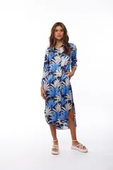 Vestido camisero midi con estampado de hojas de palmera en tonos azul, blanco y negro. Tiene cuello camisero, mangas largas con puños abotonados, cierre frontal con botones y bolsillos laterales.