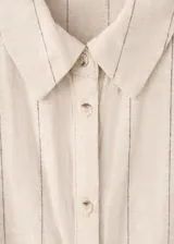 Camisa de lino y algodón color beige con estampado de raya diplomática, cuello camisero, manga corta y detalle de nudo en la cintura con cierre delantero de botones.