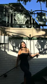 Vestido midi negro ajustado, con tirantes finos, escote recto y detalle de frunce en el lateral del busto. Presenta una abertura lateral en la falda.