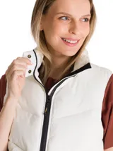 Chaleco puffer acolchado color beige, con cuello alto, cierre frontal de cremallera y bolsillos laterales.
