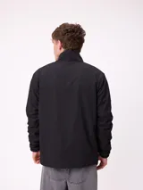 Campera reversible con cuello alto y cierre frontal. Un lado presenta tejido de polar con estampado geométrico en tonos verdes y bolsillo con cierre en el pecho, mientras que el otro lado es de nylon. Cuenta con puños elásticos y bolsillos laterales.