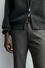 Pantalón chino de corte ajustado, color beige, con bolsillos laterales y bolsillos traseros de vivo. Cuenta con cierre frontal de cremallera y botón.