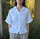 Camisa verde militar de lino italiana con botones de nácar, corte holgado, cuello camisero y mangas cortas con dobladillo.