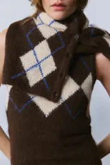 Chaleco de punto con cuello redondo y diseño sin mangas. Presenta un patrón de rombos en tonos marrón y beige con detalles en azul.