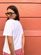 Remera blanca de corte holgado con estampa frontal en color azul que ilustra una escena de aperitivo con botella, copa y plato, acompañada por la palabra 'aperitivo' y la hora '13:00 PM'.