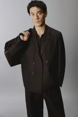 Blazer cruzada de hombre en color marrón oscuro, de corte regular fit, confeccionada en lino. Cuenta con solapas de muesca, bolsillos con solapa en la cadera y doble botonadura frontal.