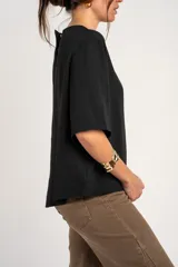 Blusa negra de manga corta y cuello redondo, confeccionada en tejido ligero y fluido.