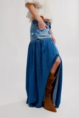 Falda maxi de denim con canesú de tiro alto y cuerpo fruncido, abertura frontal y ruedo sin terminar. Combina paneles con diferentes lavados de jean.