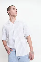 Camisa de manga corta a rayas verticales color blanco y celeste, con cuello solapa y corte regular.