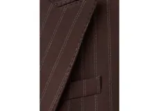 Blazer de corte sastrero en color marrón oscuro con diseño de rayas diplomáticas verticales. Presenta solapas clásicas, cierre frontal con botones y bolsillos laterales con solapa.