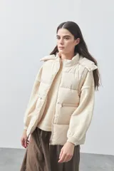 Chaleco puffer negro con diseño acolchado, capucha desmontable y cierre frontal. Cuenta con cordones ajustables en la cintura y bolsillos laterales.