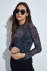 Body de mangas largas con cuello alto, confeccionado en tejido de tul semitransparente con estampado animal print en tonos grises y negros.