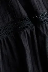 Pollera larga de color negro con elegantes alforzas e inserciones de encaje. Modelo de corte holgado con cintura elástica en la parte posterior.