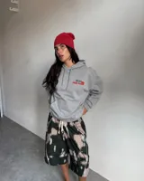 Hoodie de corte regular en color gris melange, con capucha, mangas largas y bolsillos tipo canguro. Presenta un estampado gráfico en la espalda con la inscripción 'Fletes' y una ilustración de una grúa transportando una planta.